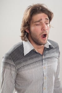 Yawning man in grey shirt suffering from sleep deprivation