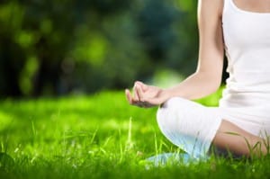 Female meditator sitting on the grass increasing her happiness